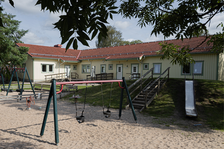 Förskolan Björsgården en solig sommardag omgiven av grön lummighet.